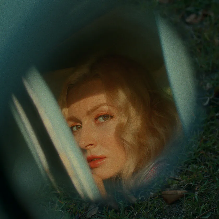 Agfa Agfacolor Portrait XPS 161 — Blonde woman seen through a car window, framed by grass and soft reflections.
