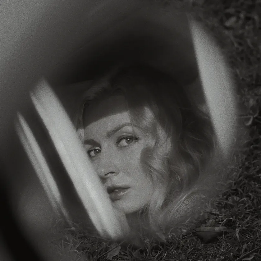 Agfa Scala 200x — Black-and-white portrait of a blonde woman seen through a car window and grass.
