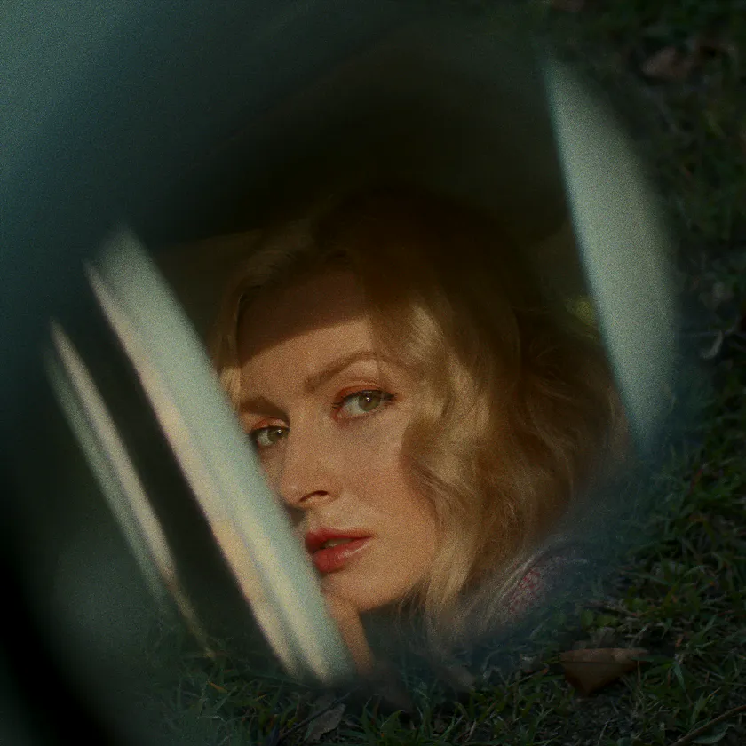 Fujicolor Superia 1601 — Blonde woman seen through a car window, framed by grass and soft reflections.
