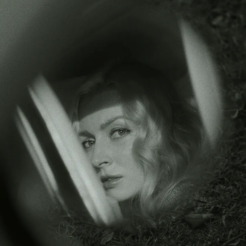 Ilford HP5 Plus 401 — Black-and-white portrait of a blonde woman seen through a car window and grass.