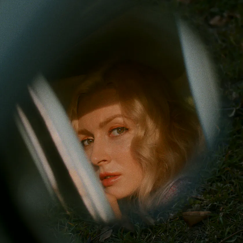 Konica Minolta VX400 Super — Blonde woman seen through a car window, framed by grass and soft reflections.
